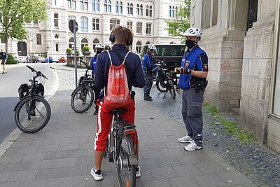 Radfahrer auf dem Bürgersteig wird durch einen Polizisten angehalten