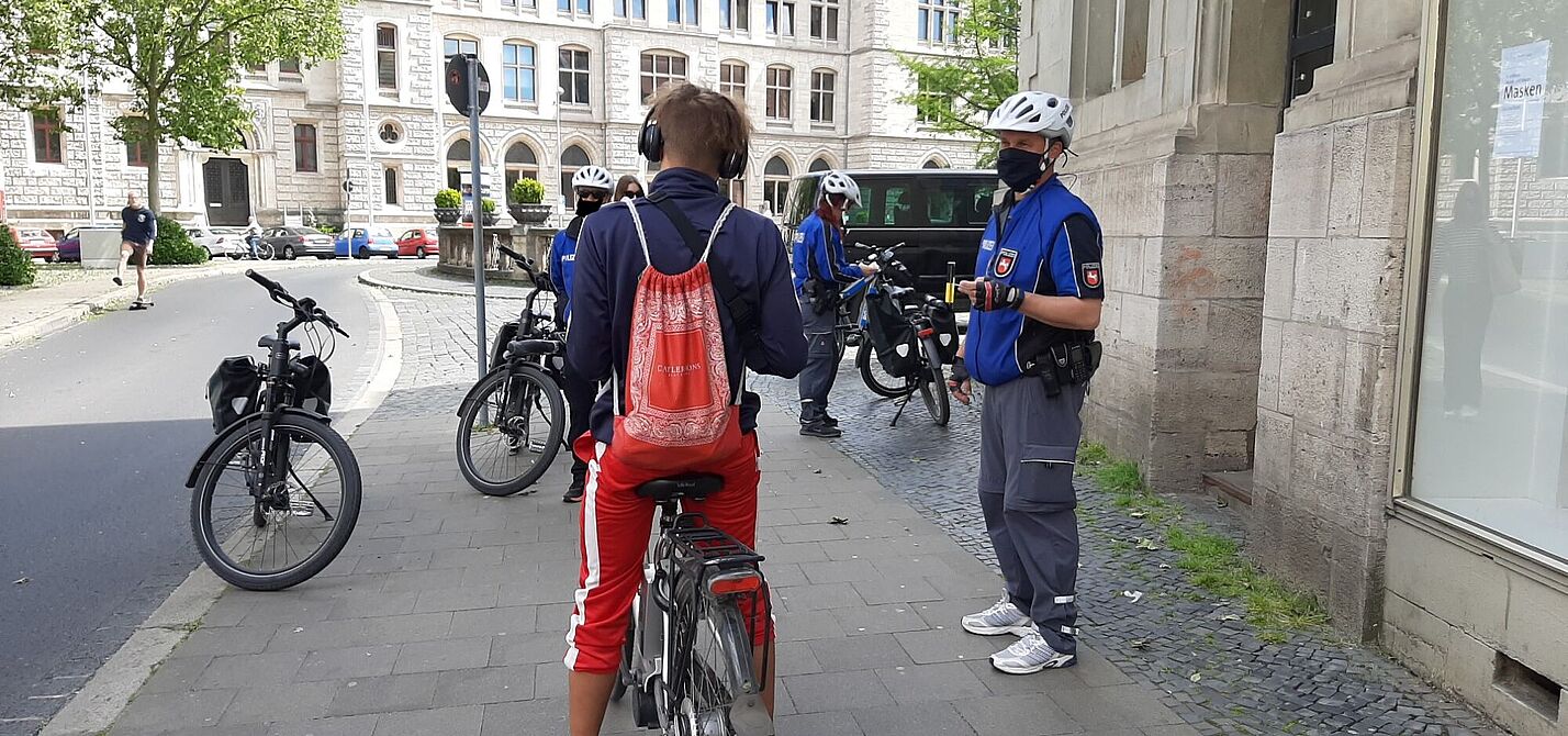 Radfahrer auf dem Bürgersteig wird durch einen Polizisten angehalten