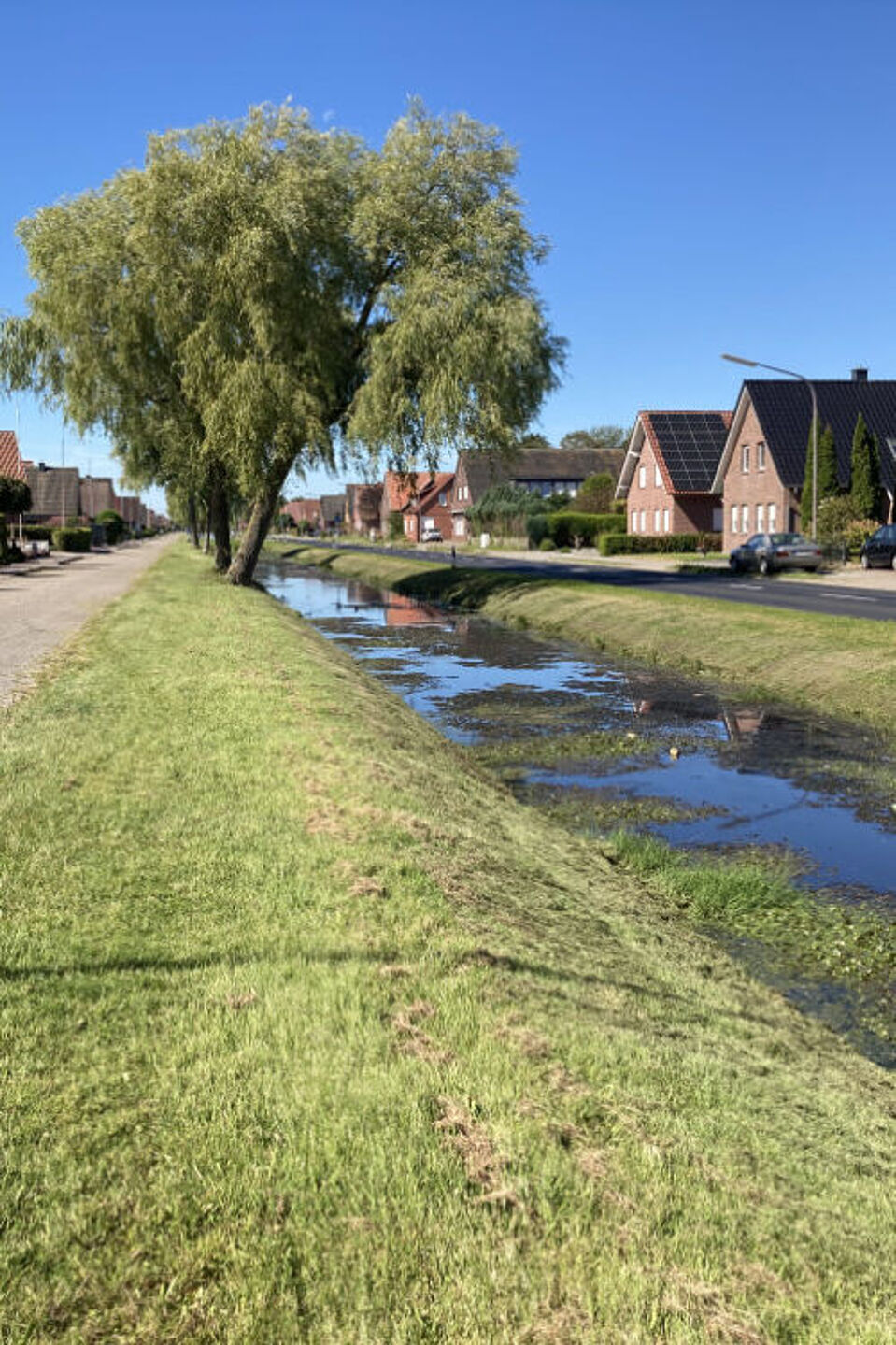 Fehnkanal Das Bild zeigt einen Fehnkanal in Ostfriesland mit Straßen und Häuserzeilen rechts und links