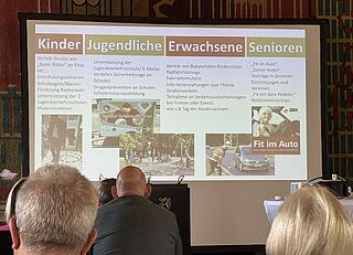 Das Bild zeigt einen Konferenzraum; auf die Leinwand ist eine Darstellung mit Verkehrsthemen projiziert