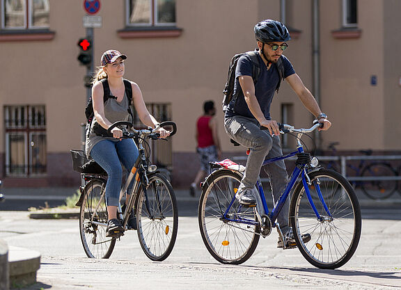 Das Bild zeigt zwei jungen Menschen, die in der Stadt radeln