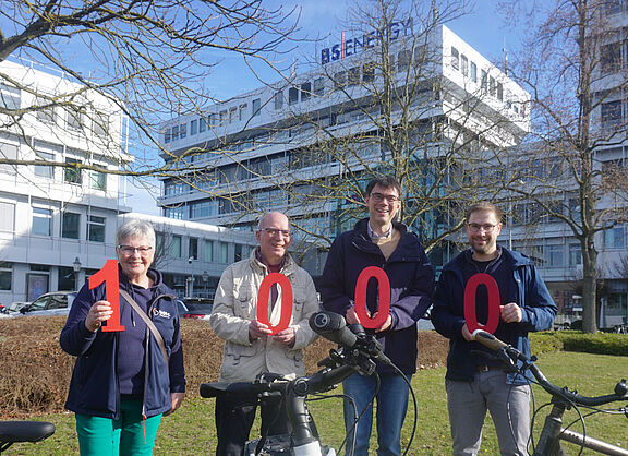 Das Bild zeigt zwei Mitglieder des ADFC Braunschweig und zwei Mitarbeiter von BS Energy die die Ziffern 1, 0, 0, 0 in den Händen halten