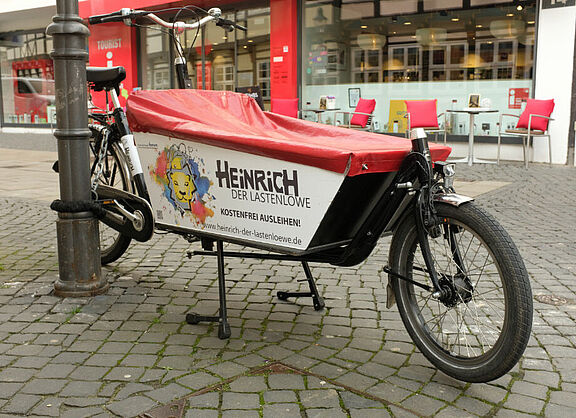 Das Bild zeigt ein Lastenfahrrad mit dem Aufdruck: Heinrich der Lastenlöwe - kostenfrei ausleihen