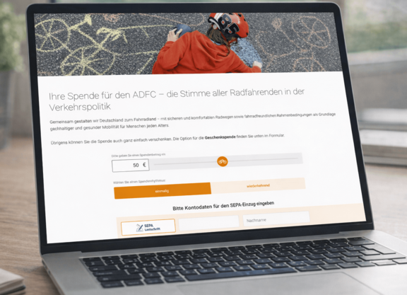 Spendenformular Desktopansicht Ein Laptop steht auf einem Tisch. Auf dem Bildschirm ist die Spendenseite des ADFC zu sehen.