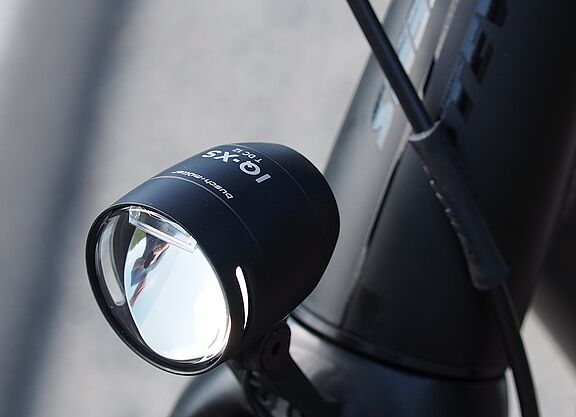 Schwarzer LED-Fahrradscheinwerfer am silbernen Fahrradlenker montiert.
